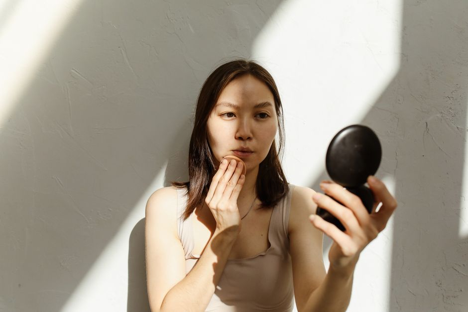 鏡の前で肌の状態を確認する女性