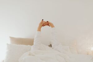 朝起きてすぐスマホを見るに悩む女性のイメージ